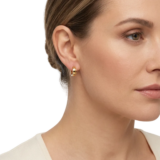 Gładkie złote kolczyki huggie na modelce na białym tle