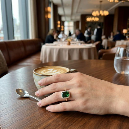 Jeden pierścionek z zielonym kamieniem na dłoni przy kawie w restauracji